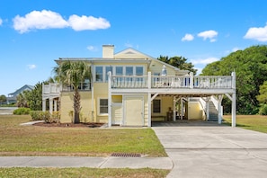 A two-story house with a balcony, a garage, and a covered porch area. - Spacious 7BR coastal retreat, pet-friendly, ocean views, large yards, perfect for families & groups (North Myrtle Beach)
