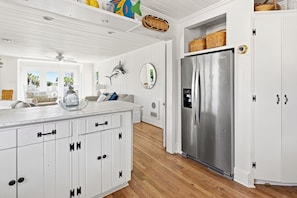 A kitchen with white cabinetry, a stainless steel refrigerator, and a wooden floor. - Spacious 7BR coastal retreat, pet-friendly, ocean views, large yards, perfect for families & groups (North Myrtle Beach)