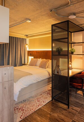 Habitació d'hotel moderna amb un llit gran, escriptori, cadira i un panell decoratiu.