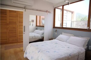 Quarto com cama, guarda-roupa de madeira e janela com vista.