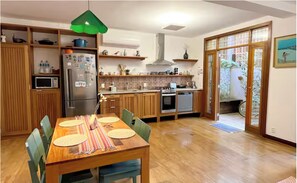 Une cuisine moderne avec des meubles en bois, une table à manger avec des chaises et un luminaire suspendu vert.