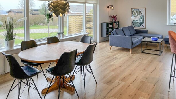 Una sala de estar moderna con comedor, ventanas grandes y vistas al exterior.