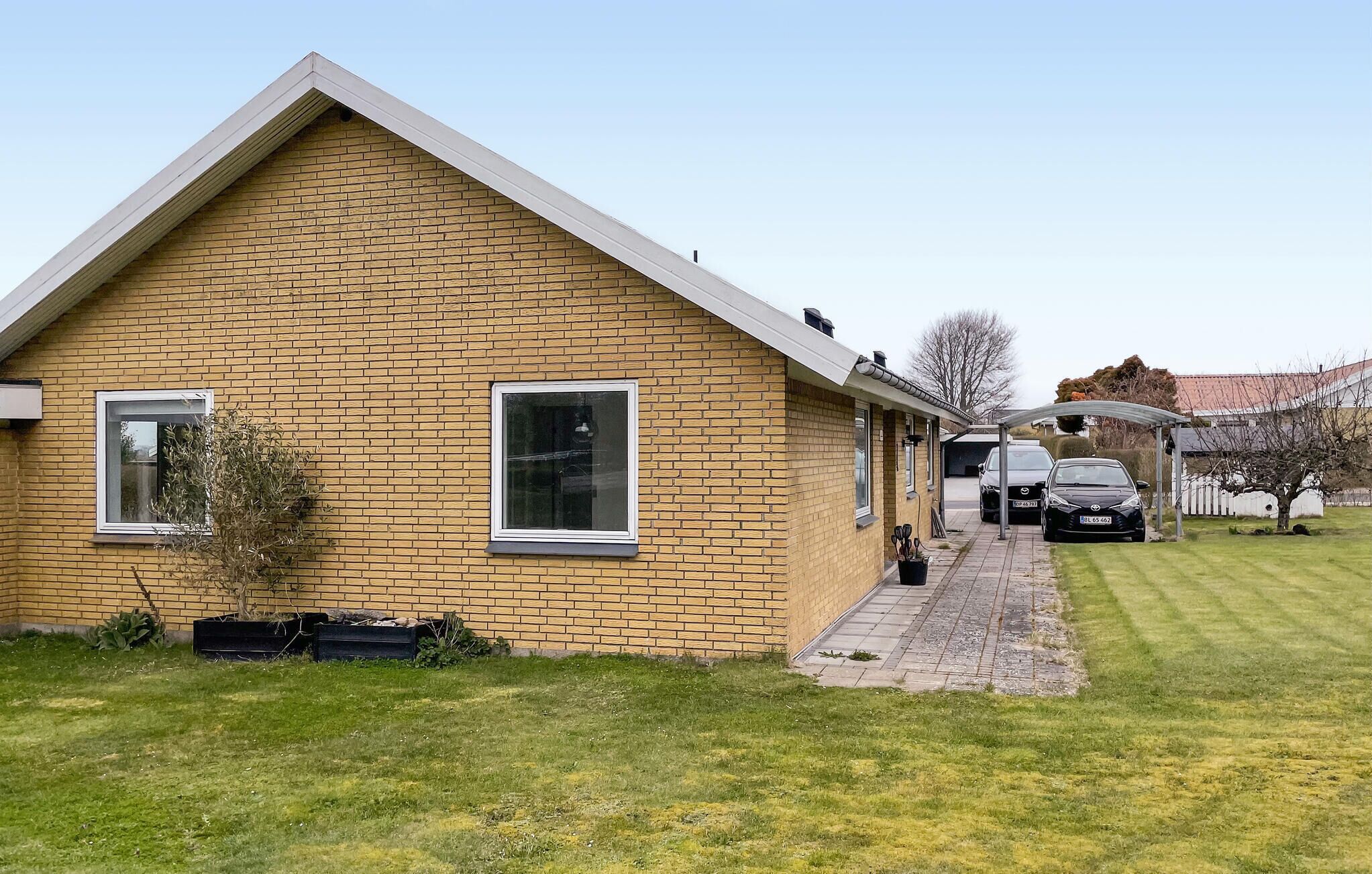 A single-story brick house with a sloped roof, a small front porch, and a garage with two cars parked inside.