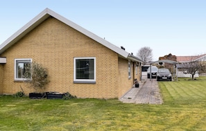 A single-story brick house with a sloped roof, a small front porch, and a garage with two cars parked inside. - Awesome home in Faaborg with WiFi (Faaborg)