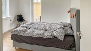 Un dormitorio con cama, silla, puerta y ventana.