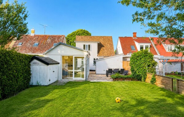 Een woonhuis met een verzorgd gazon, een tuinhuisje en een terras.