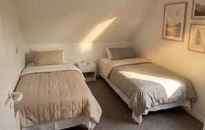 Een slaapkamer met twee bedden, een nachtkastje en een aan de muur hangend schilderij.