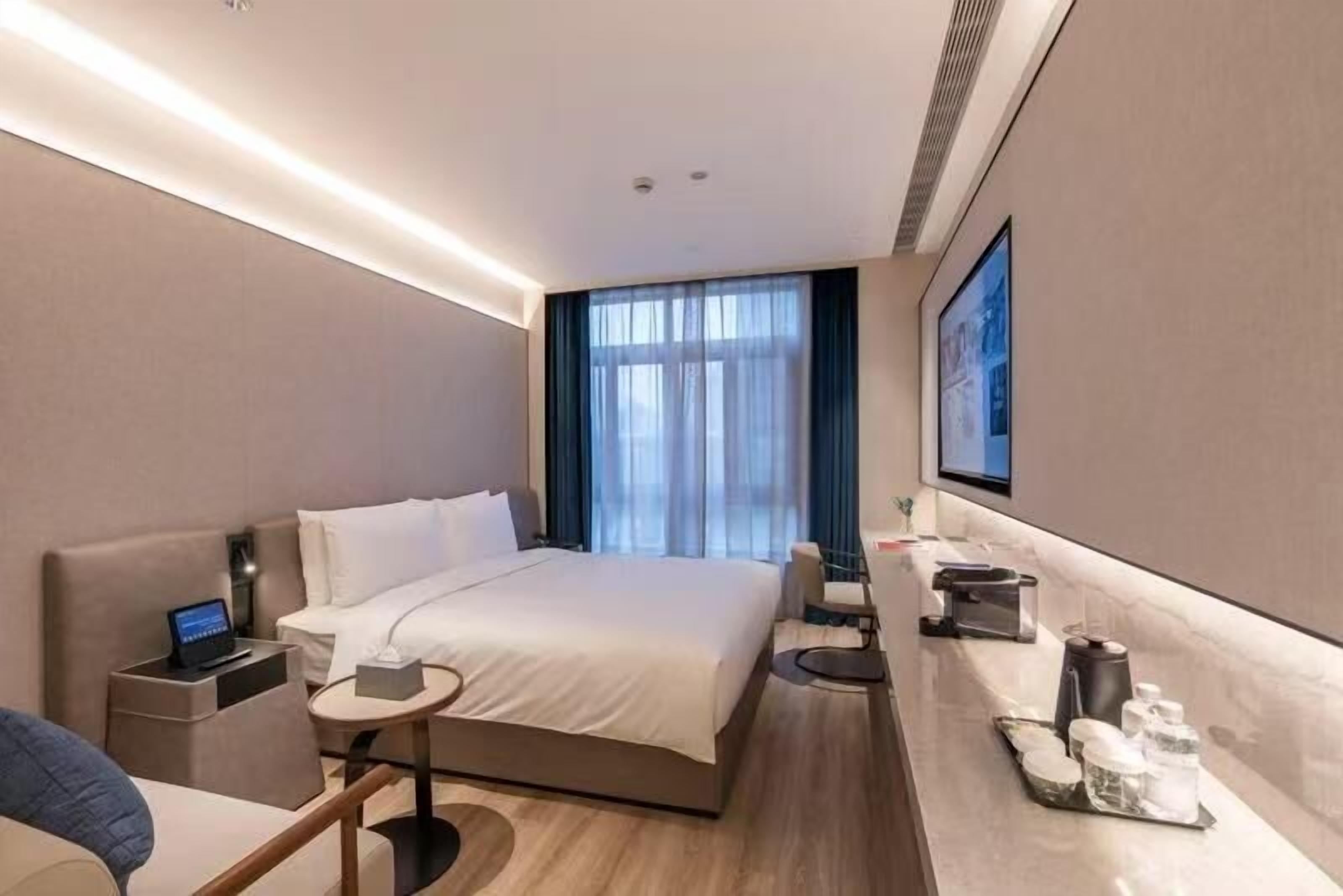 Une chambre d’hôtel moderne avec un grand lit, des tables de chevet, un bureau et un téléviseur.