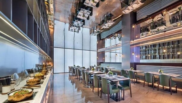 A modern dining area with long tables, chairs, and a buffet line with various dishes. - Orange Crystal Shanghai Lujiazui Expo (Shanghai)