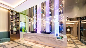 A modern hotel lobby with a reception desk, seating area, and a large window. - Orange Crystal Shanghai Lujiazui Expo (Shanghai)