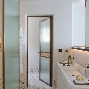 A bathroom with a glass door, a sink with toiletries, and a towel hanging on the wall. - Nammos Hotel Mykonos & Villas (Mykonos)