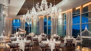 A dining area with multiple tables, chandeliers, and large windows. - Bright 2-bedroom a Condo with AC in fabulous Riviera Maya (Playa del Carmen,)