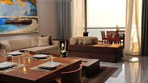 A modern living room with a sofa, dining table set, and a painting of a beach scene. - Bright 2-bedroom a Condo with AC in fabulous Riviera Maya (Playa del Carmen,)