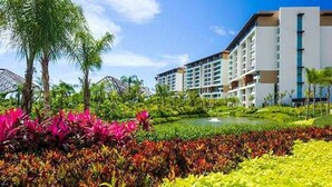 A hotel with multiple floors, a landscaped garden with colorful plants, and a clear blue sky. - Bright 2-bedroom a Condo with AC in fabulous Riviera Maya (Playa del Carmen,)