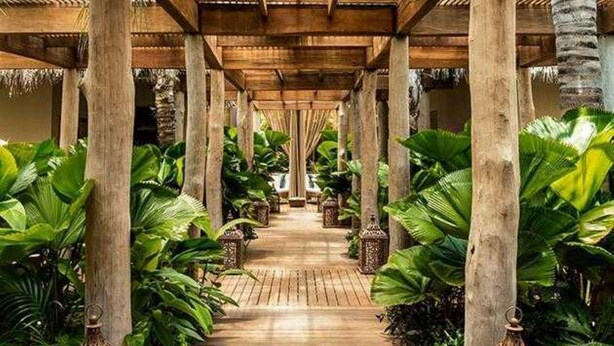 A covered walkway with wooden pillars and tropical plants. - Bright 2-bedroom a Condo with AC in fabulous Riviera Maya (Playa del Carmen,)