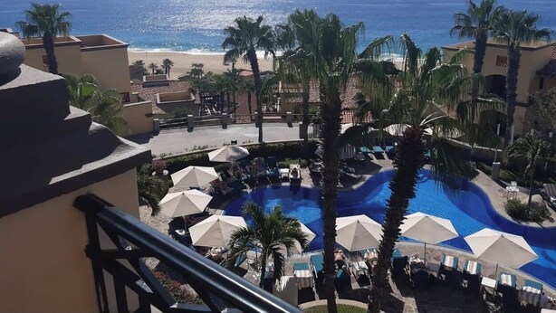 Un resort con piscina, palmeras y vista al océano.