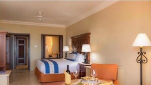 Habitación de hotel con cama, una mesa de comedor con comida y bebidas, una silla, una lámpara y un armario.