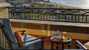Un balcón con una mesa dispuesta para dos personas, con vista a la playa y al océano.