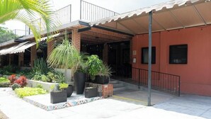 A building with a covered entrance, potted plants, and a tiled patio area. - Capital O La Joya Del Lago (Chapala)