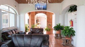 A living room with a leather sofa, a stone fountain, and potted plants. - Capital O La Joya Del Lago (Chapala)