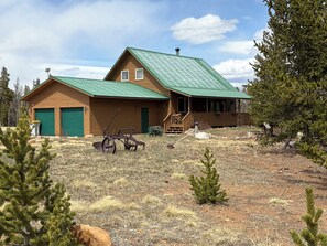 A wooden cabin with a green roof, a covered porch, and a front yard with sparse vegetation. - 2 bedroom 2 bath cozy cabin on 40 acres in Fairplay. (Fairplay)
