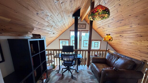 A cozy attic room with a wooden ceiling, a leather sofa, a desk with a chair, and a bookshelf. - 2 bedroom 2 bath cozy cabin on 40 acres in Fairplay. (Fairplay)