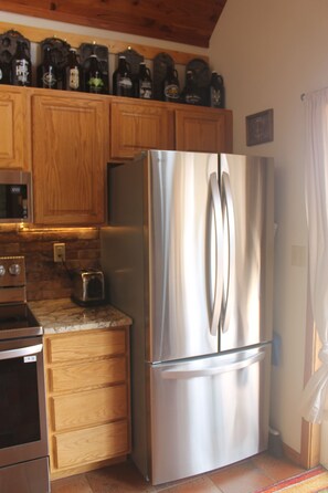 A kitchen with wooden cabinets, a stainless steel refrigerator, a toaster, and a microwave. - 2 bedroom 2 bath cozy cabin on 40 acres in Fairplay. (Fairplay)
