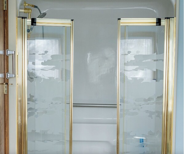 A bathroom with a glass-enclosed shower, a toilet, and a sink.
