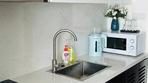 A modern kitchen with a double sink, a built-in microwave, and a black induction cooktop. - Cozy studio for couple and small family in Sapphire Ha Long (Ha Long)