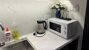 A kitchen with a microwave, a coffee maker, a sink, and a vase with flowers on the counter. - Cozy studio for couple and small family in Sapphire Ha Long (Ha Long)
