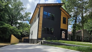Um edifício moderno de dois andares com garagem, rodeado de árvores e céu aberto.
