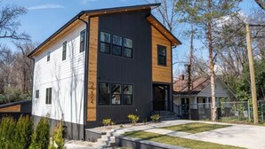 Uma casa moderna de dois andares com garagem, varanda frontal e gramado bem cuidado.