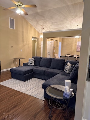 A living room with a sectional sofa, a round coffee table, and a ceiling fan. - 4-bedroom house in Fairburn close to the airport. Perfect for World Cup visits. (Fairburn)
