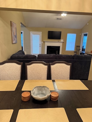 A living room with a fireplace, a television, and a dining area with a table and chairs. - 4-bedroom house in Fairburn close to the airport. Perfect for World Cup visits. (Fairburn)
