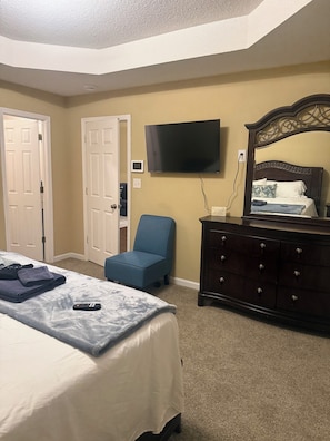 Une chambre à coucher avec un lit, une télévision, une commode et une chaise.