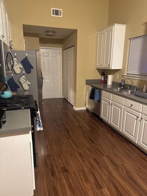 A kitchen with wooden flooring, white cabinets, a stove, oven, and a refrigerator. - 4-bedroom house in Fairburn close to the airport. Perfect for World Cup visits. (Fairburn)