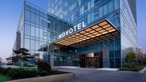 Un hotel moderno con fachada de vidrio, una entrada destacada y un exterior bien cuidado.