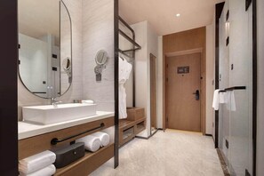 A modern bathroom with a large mirror, a sink, and a wooden vanity. - Novotel Lianyungang Haizhou (Guangzhou)