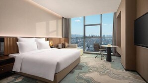Una habitación de hotel moderna con una cama grande, un escritorio, una silla y una televisión.