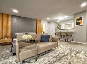 A modern living room with a sofa, a coffee table, and a patterned rug. - Your Montrose Studios Sleeps 80/40BR/40BA/30PA (Houston)