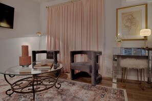 Una habitación con una mesa de vidrio, dos sillas, un tapete, una lámpara y un cuadro en la pared.