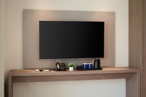 A modern reception desk with a flat-screen TV mounted above it, a telephone, a small potted plant, and a coffee machine. - The Hotel Sokcho (Sokcho)