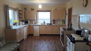 Une cuisine compacte avec des meubles en bois, un lave-vaisselle, une cuisinière et une fenêtre donnant sur un beau paysage.