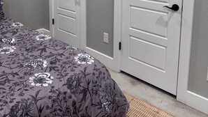 Ein Schlafzimmer mit einem Bett, zwei weißen Türen und einer grauen Wand.