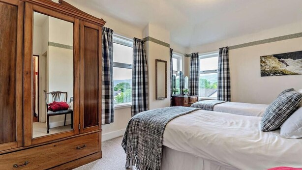 Un dormitorio con un armario grande, dos camas, un espejo y vistas a zonas verdes.