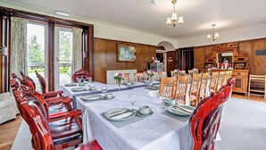 Comedor con una larga mesa dispuesta para una comida, sillas de madera y un candelabro.