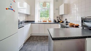Una cocina moderna con armarios blancos, encimera negra y una ventana que deja entrar luz natural.