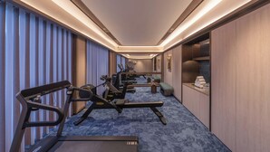Ein Hotelzimmer mit Fitnessbereich, inklusive Laufband, Crosstrainer und Gewichten.