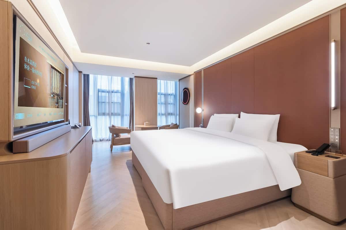 Een hotelkamer met een groot bed, nachtkastjes, een televisie en uitzicht.