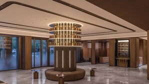 Eine moderne Lobby mit einer zylindrischen Leuchte in der Mitte, Holzvertäfelung und einer Glastür zum Außenbereich.